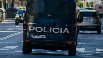 Rear view of a police van with the word 'Policia' on the back, driving on a city street. - Olive Oil Times