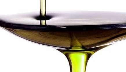Olive oil being poured into a shallow bowl, showcasing its rich color and texture. - Olive Oil Times