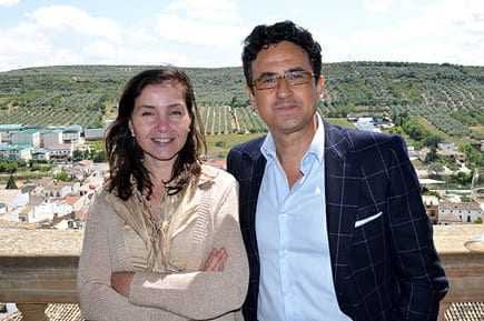 Two individuals standing together outdoors, smiling at the camera with a landscape in the background. - Olive Oil Times