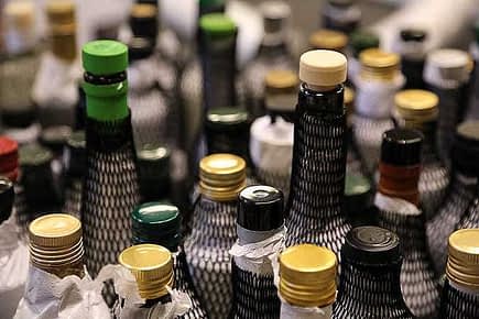 A variety of olive oil bottles with different colored caps and labels arranged closely together. - Olive Oil Times