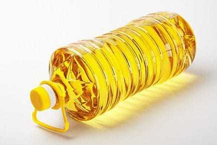 Transparent plastic bottle filled with yellow canola oil, featuring a yellow cap and handle. - Olive Oil Times