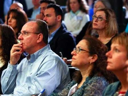 A diverse group of individuals attentively listening during a conference presentation. - Olive Oil Times
