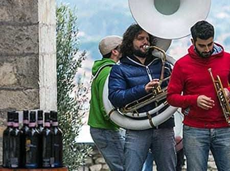 Three musicians performing outdoors with a tuba, trumpet, and other instruments. - Olive Oil Times