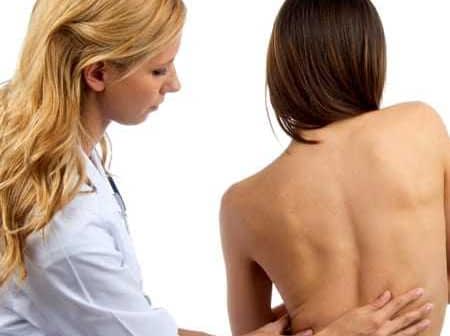 Healthcare professional examining the back of a patient in a clinical setting. - Olive Oil Times