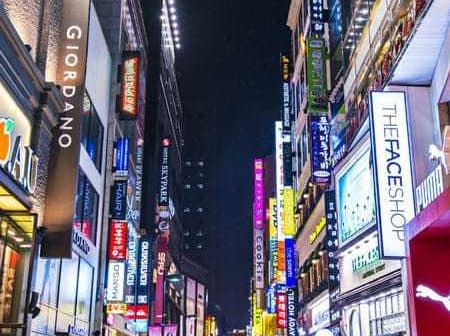 Illuminated shopping street in South Korea with various storefronts and signs at night. - Olive Oil Times