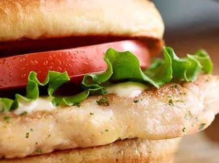 Grilled chicken sandwich featuring lettuce, tomato, and mayonnaise on a bun. - Olive Oil Times