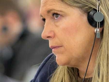Woman wearing headphones, focused on a discussion during a conference or meeting. - Olive Oil Times