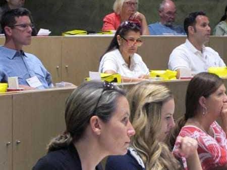 Group of individuals seated in a classroom, attentively listening during a presentation. - Olive Oil Times