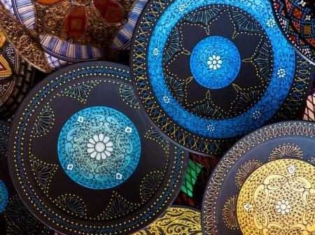 Collection of decorative hand-painted ceramic plates featuring intricate designs in various colors. - Olive Oil Times