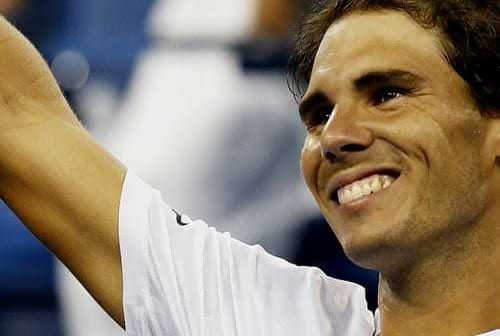 Tennis player Rafael Nadal smiling and raising his hand in celebration at a match. - Olive Oil Times