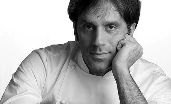 Black and white portrait of a chef resting his chin on his hand, wearing a white chef's uniform. - Olive Oil Times