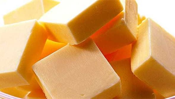 Several yellow butter cubes stacked together in a clear bowl. - Olive Oil Times