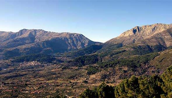 Panoramic view of Tietar Valley featuring mountains and greenery under a clear sky. - Olive Oil Times