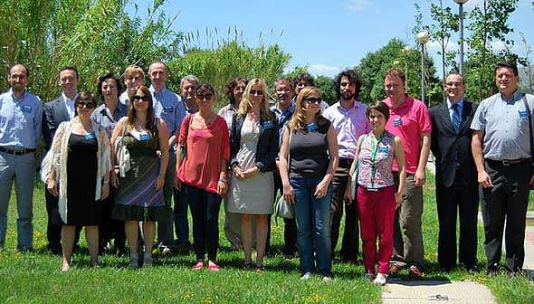A group of diverse individuals posing together outdoors in a green area with trees and grass. - Olive Oil Times