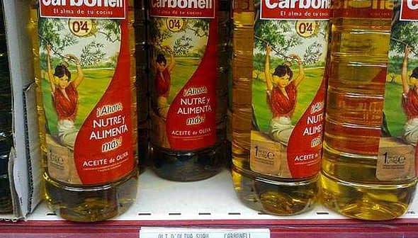 Three bottles of Carbonell olive oil displayed on a store shelf with a price tag below. - Olive Oil Times