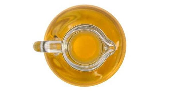 A glass cruet filled with yellow olive oil viewed from above. - Olive Oil Times