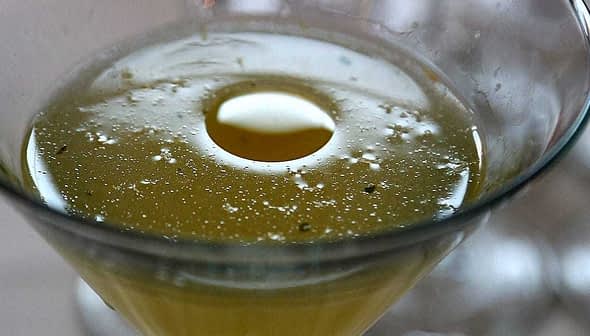Close-up of a cocktail in a glass with bubbles and a circular garnish. - Olive Oil Times