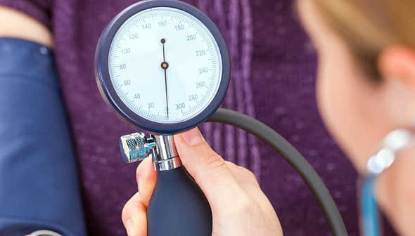 A healthcare professional measuring blood pressure with a sphygmomanometer on a patient's arm. - Olive Oil Times