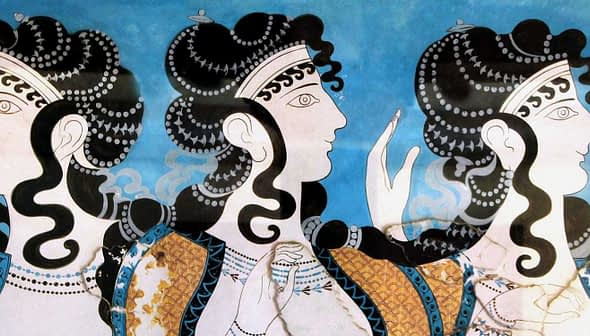 Ancient fresco showing three women with elaborate hairstyles and decorative clothing against a blue background. - Olive Oil Times
