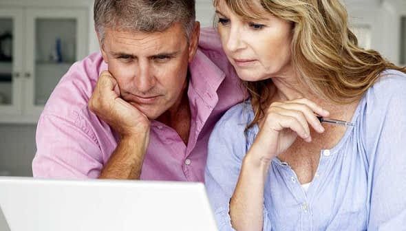 Middle-aged couple closely examining content on a laptop screen in a home setting. - Olive Oil Times