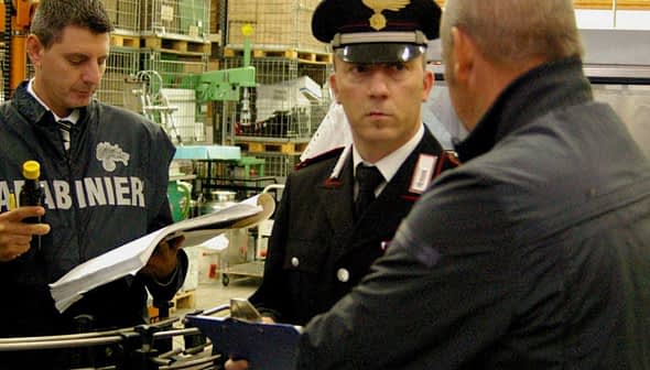 Two Italian Carabinieri officers inspecting a facility with documents and equipment. - Olive Oil Times