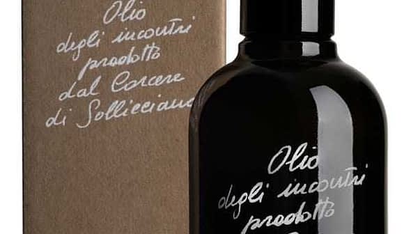 Black glass bottle of olive oil with a cardboard box featuring handwritten text. - Olive Oil Times
