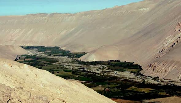 Aerial view of a valley surrounded by mountains with a river flowing through it. - Olive Oil Times