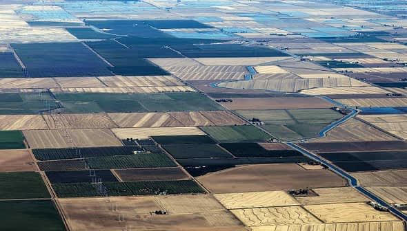 Aerial view of patchwork agricultural fields with varying colors and patterns. - Olive Oil Times