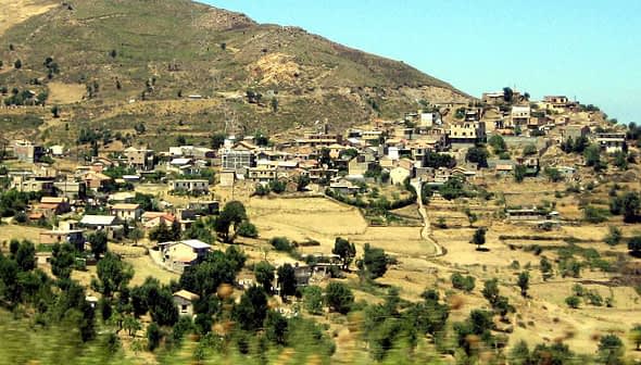 Panoramic view of a mountain village in the Kabylia region, featuring houses and agricultural land. - Olive Oil Times