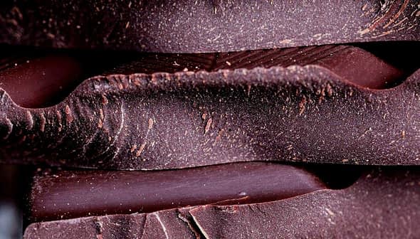 Close-up view of stacked layers of dark chocolate with a textured surface. - Olive Oil Times