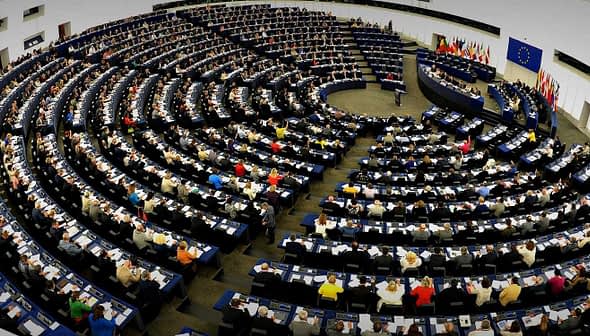 Interior view of the European Parliament with numerous members seated in a circular arrangement. - Olive Oil Times