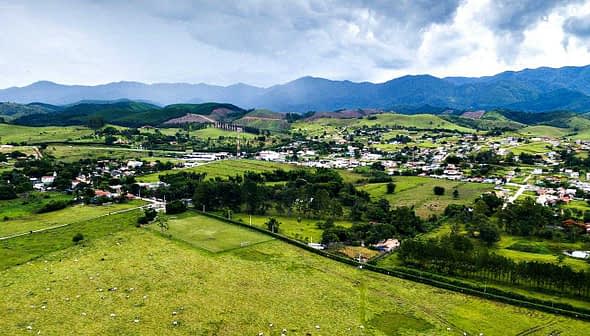 Aerial view of a rural area featuring green fields, a small town, and mountains in the background. - Olive Oil Times