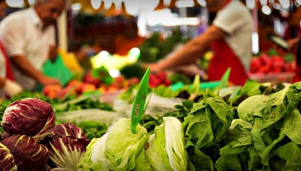 Variety of fresh vegetables including lettuce and radicchio displayed at a market stall. - Olive Oil Times