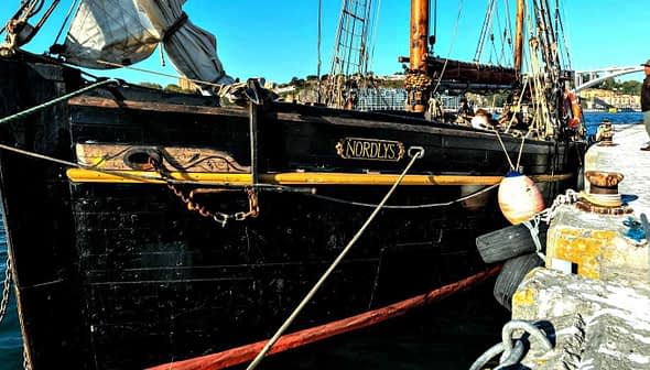 Black ship named 'Nordicus' docked at a harbor with water in the foreground. - Olive Oil Times