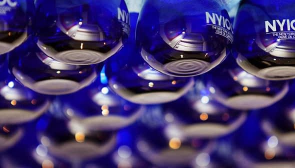 Row of blue glass bottles labeled 'NYIOOC' arranged in a display. - Olive Oil Times
