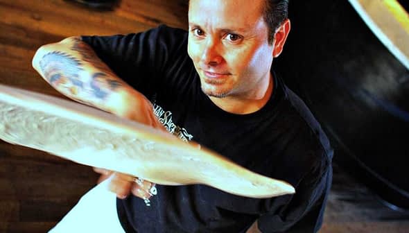 A pizza chef tossing a round piece of dough in a kitchen setting. - Olive Oil Times