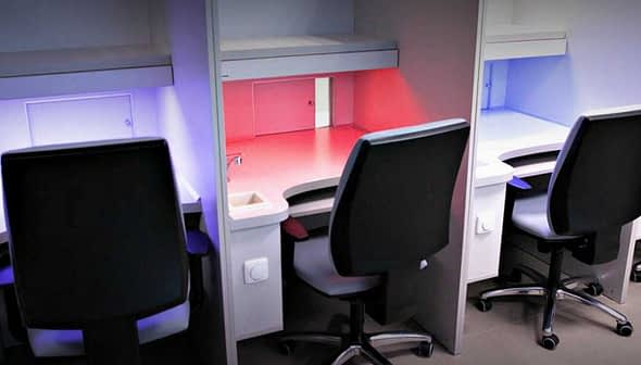 Four office workstations with ergonomic chairs and adjustable lighting in various colors. - Olive Oil Times