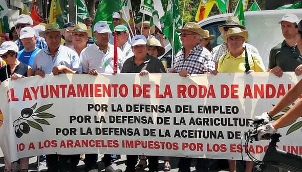 Group of protesters holding a large banner advocating for agricultural employment and olive oil support. - Olive Oil Times