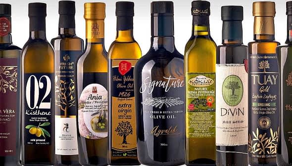 Various bottles of olive oil displayed in a row, featuring different designs and labels. - Olive Oil Times