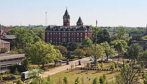 Aerial view of a university campus featuring a historic red brick building and green spaces. - Olive Oil Times