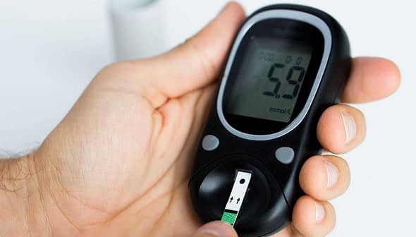 Person holding a blood glucose meter displaying a reading of 5.9 mmol/L. - Olive Oil Times