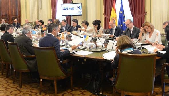 Group of individuals seated around a long table during a meeting in a conference room. - Olive Oil Times