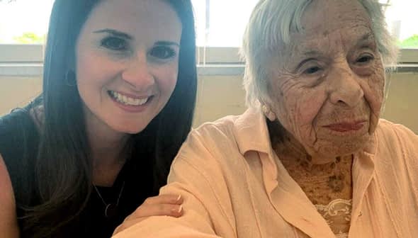 A woman with long dark hair smiling next to an elderly lady with gray hair wearing a light pink blouse. - Olive Oil Times