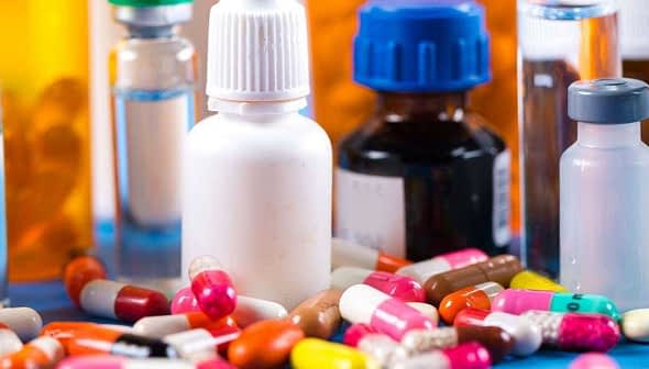 Various pharmaceutical bottles and colorful capsules arranged on a surface. - Olive Oil Times