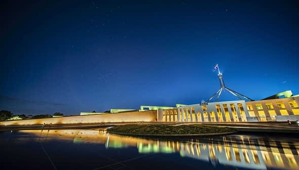 Night view of Parliament House in Canberra with reflections in the water. - Olive Oil Times