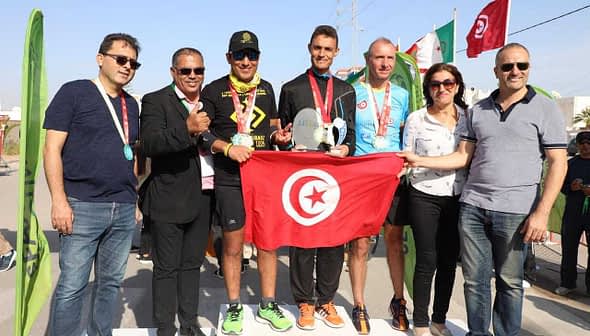 Group photo of Sfax Marathon winners holding a trophy and a Tunisian flag with event organizers. - Olive Oil Times