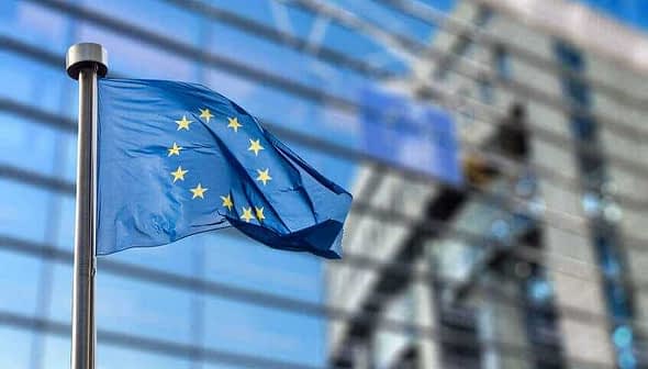 European Union flag with twelve stars on a blue background, waving in the wind. - Olive Oil Times