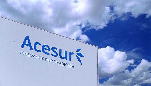 Signage displaying the Acesur logo and slogan against a blue sky with clouds. - Olive Oil Times