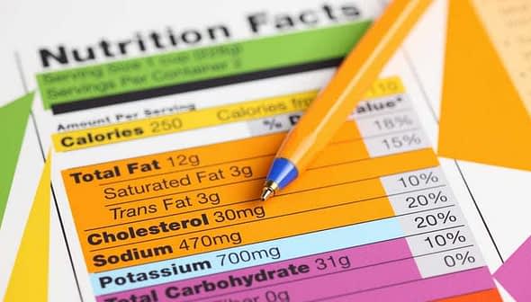 Nutrition facts label with details on calories, fat, sodium, and carbohydrates next to a blue pen. - Olive Oil Times