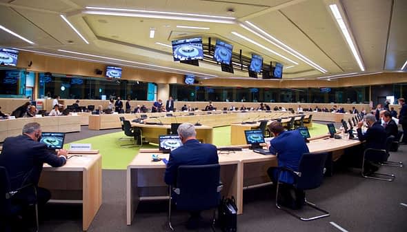 A large conference room with multiple tables and participants engaged in a meeting. - Olive Oil Times